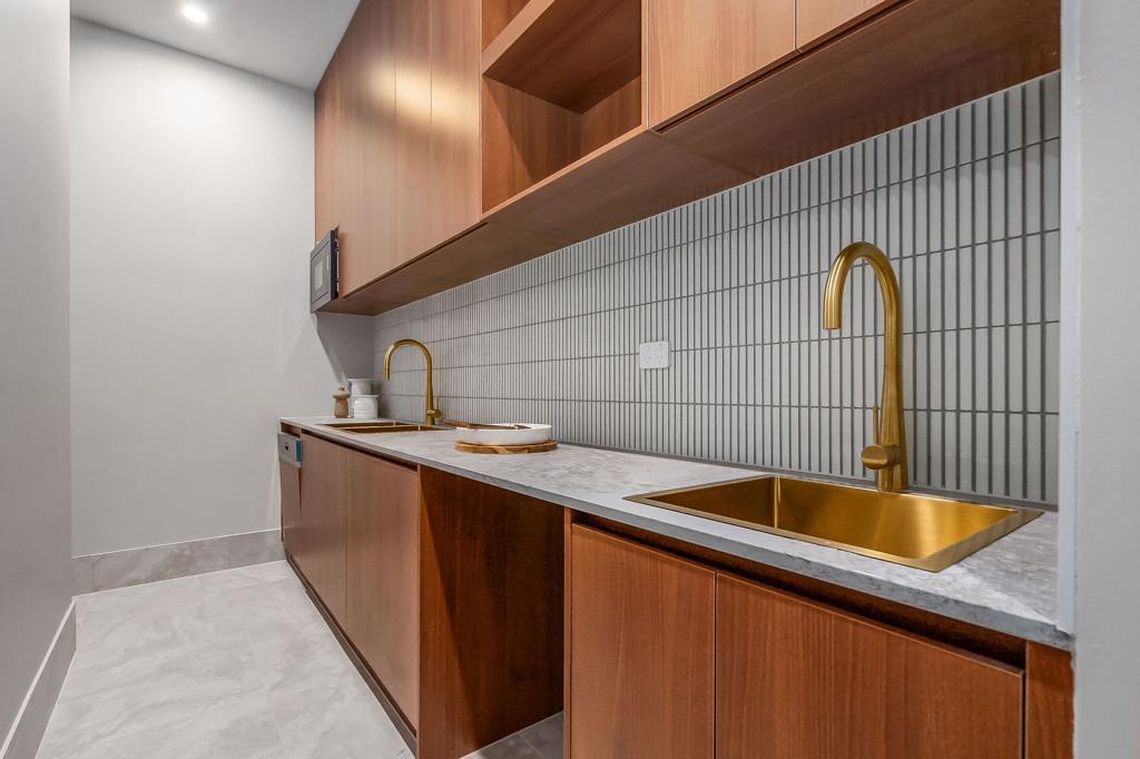 Butler's pantry with timber cabinetry and brass tapware
