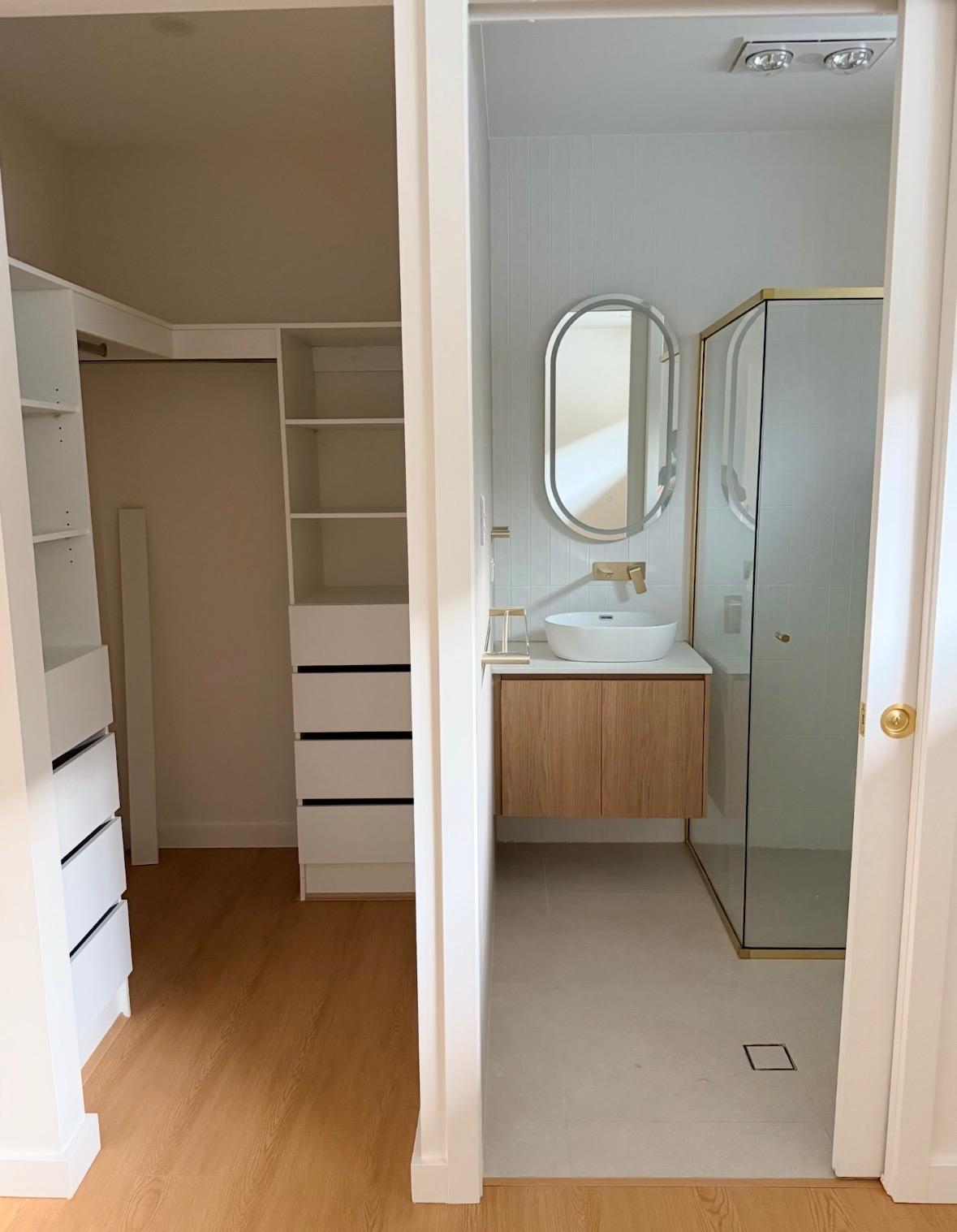 Walk-in robe with drawers and shelving beside an ensuite vanity