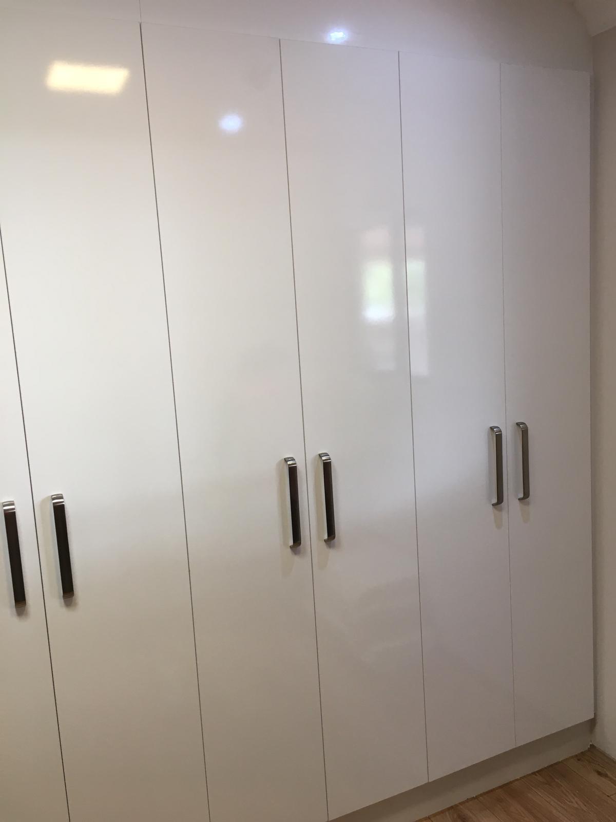 Floor-to-ceiling gloss white wardrobe doors